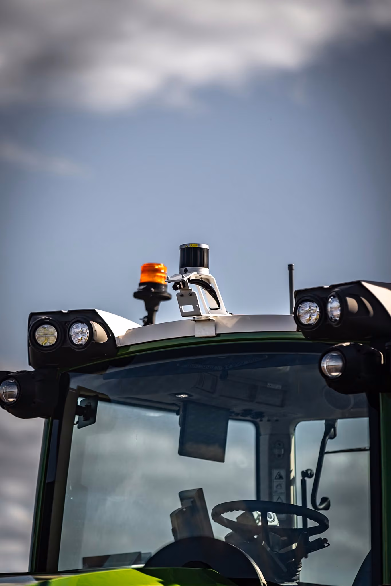 Close-up of the OutRun lidar sensor and rotating beacon mounted above a tractor cab